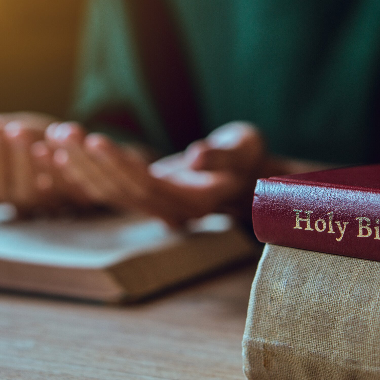 Hands of man with Bible praying.Christian life prayer to god. Man Pray for god.believe in goodness. Holding hands in prayer on a wooden table.